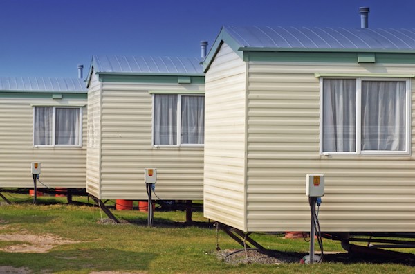 Mobile home movers inspect the condition of a single-wide home before transport, ensuring road safety and compliance with regulations mobile home movers