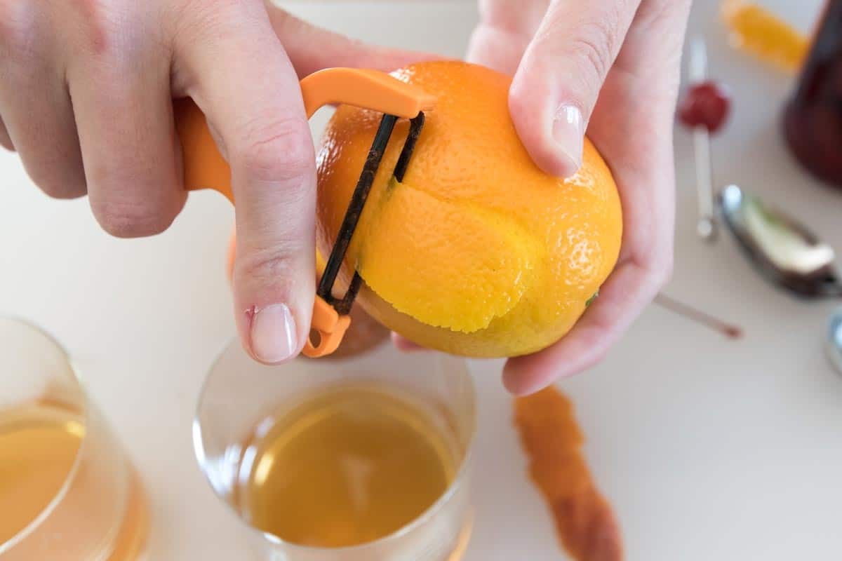 Peeling an orange for an Old Fashioned cocktail