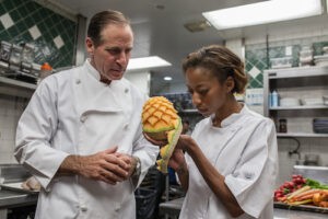 Chef preparing food in a culinary school kitchen Alt text: Chef demonstrating knife skills to a student at CASA culinary school