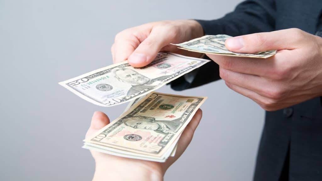 person holding cash and using a calculator