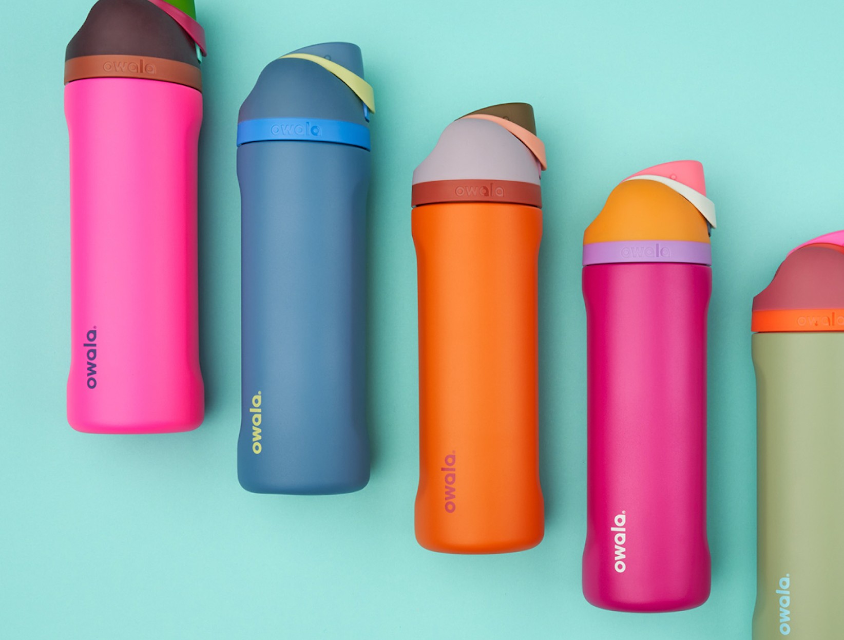 Refillable Owala water bottle sits on a table next to a laptop, signifying work and hydration.