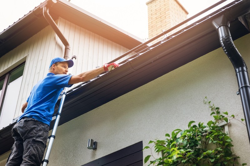Professional gutter cleaner inspecting gutters