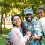 A happy military member poses with his family in a park.
