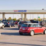 Cars lined up at a gas station, showcasing fuel prices