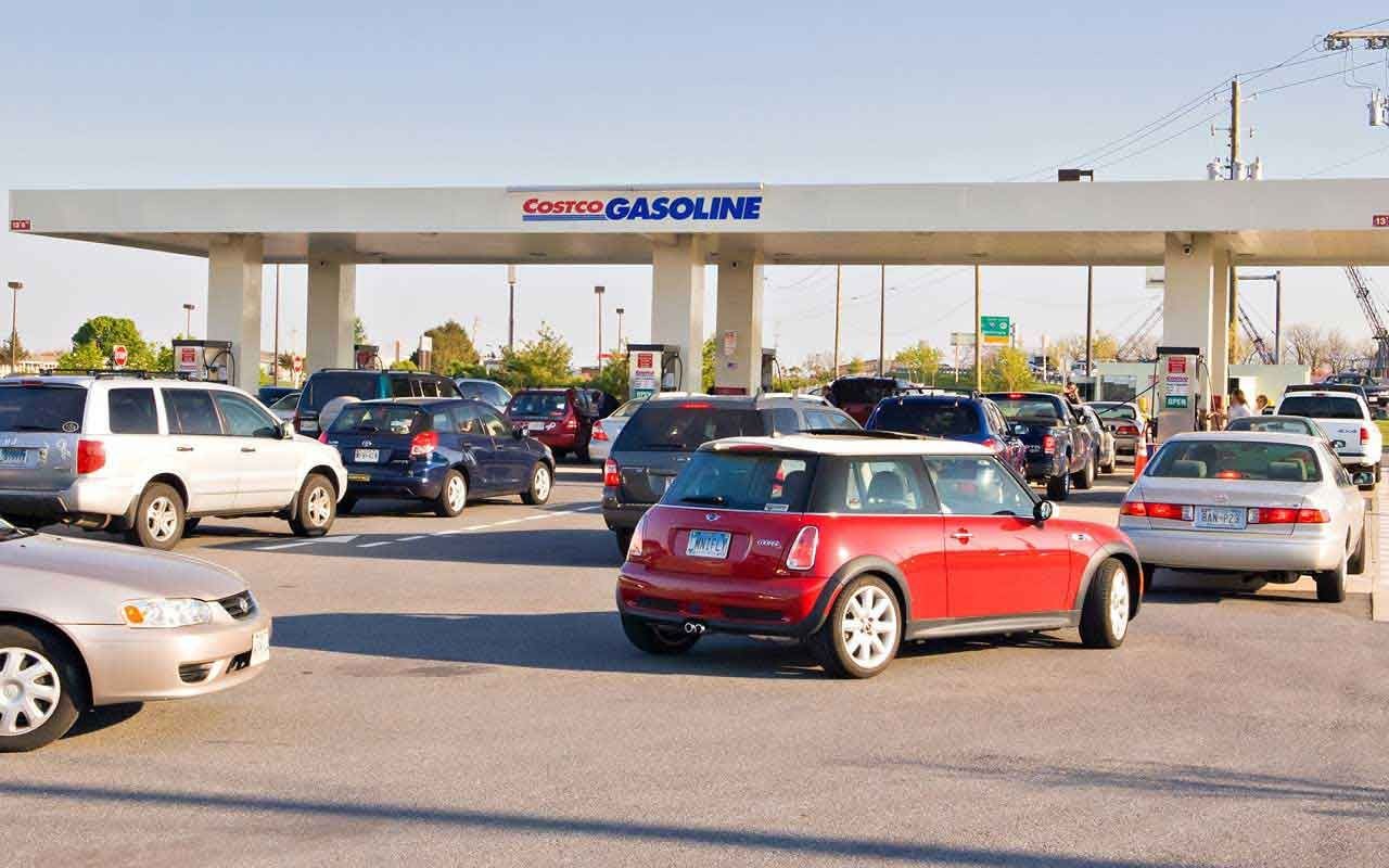 Cars lined up at a gas station, showcasing fuel prices