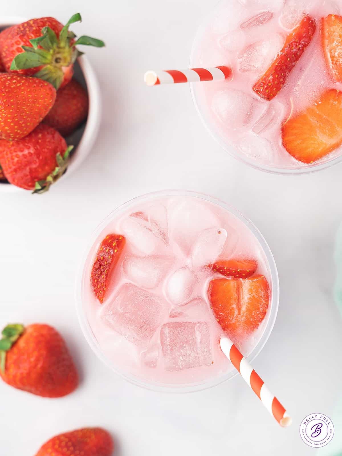 Two homemade starbucks pink drinks, garnished with fresh fruit
