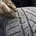 Mechanic Marking a Punctured Tire with A Nail Embedded in The Tread