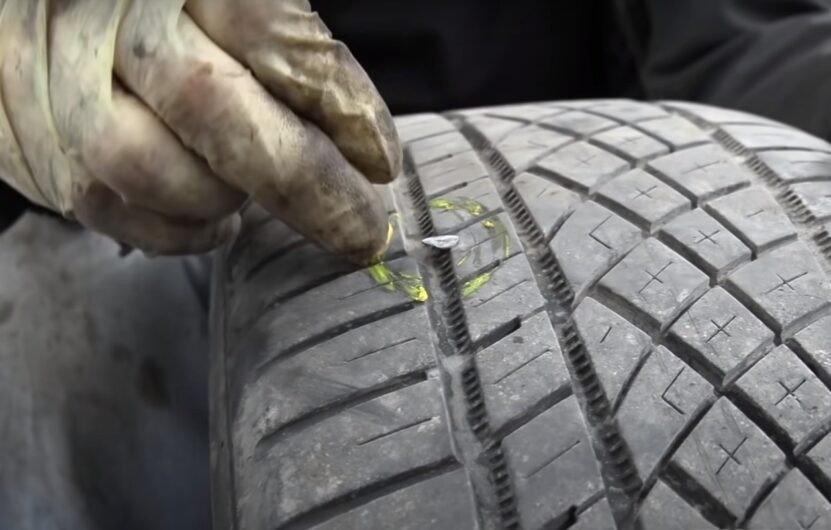Mechanic Marking a Punctured Tire with A Nail Embedded in The Tread