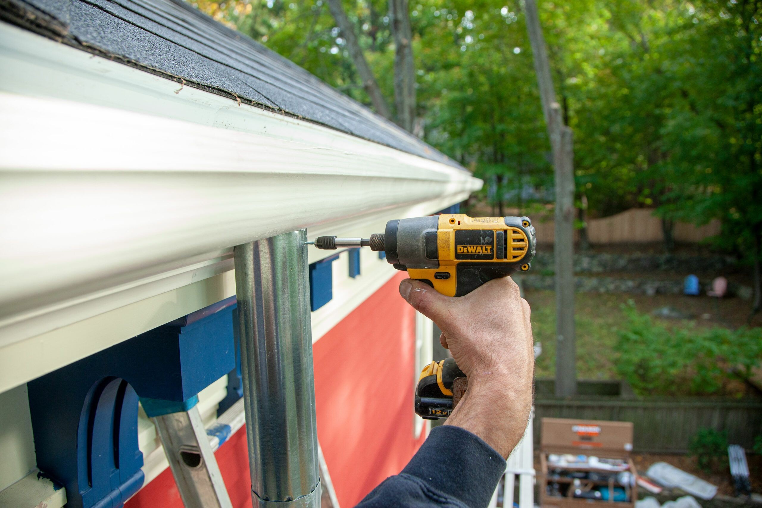 Installing a downspout to the gutter, showing how to connect the downspout outlet and secure it with rivets