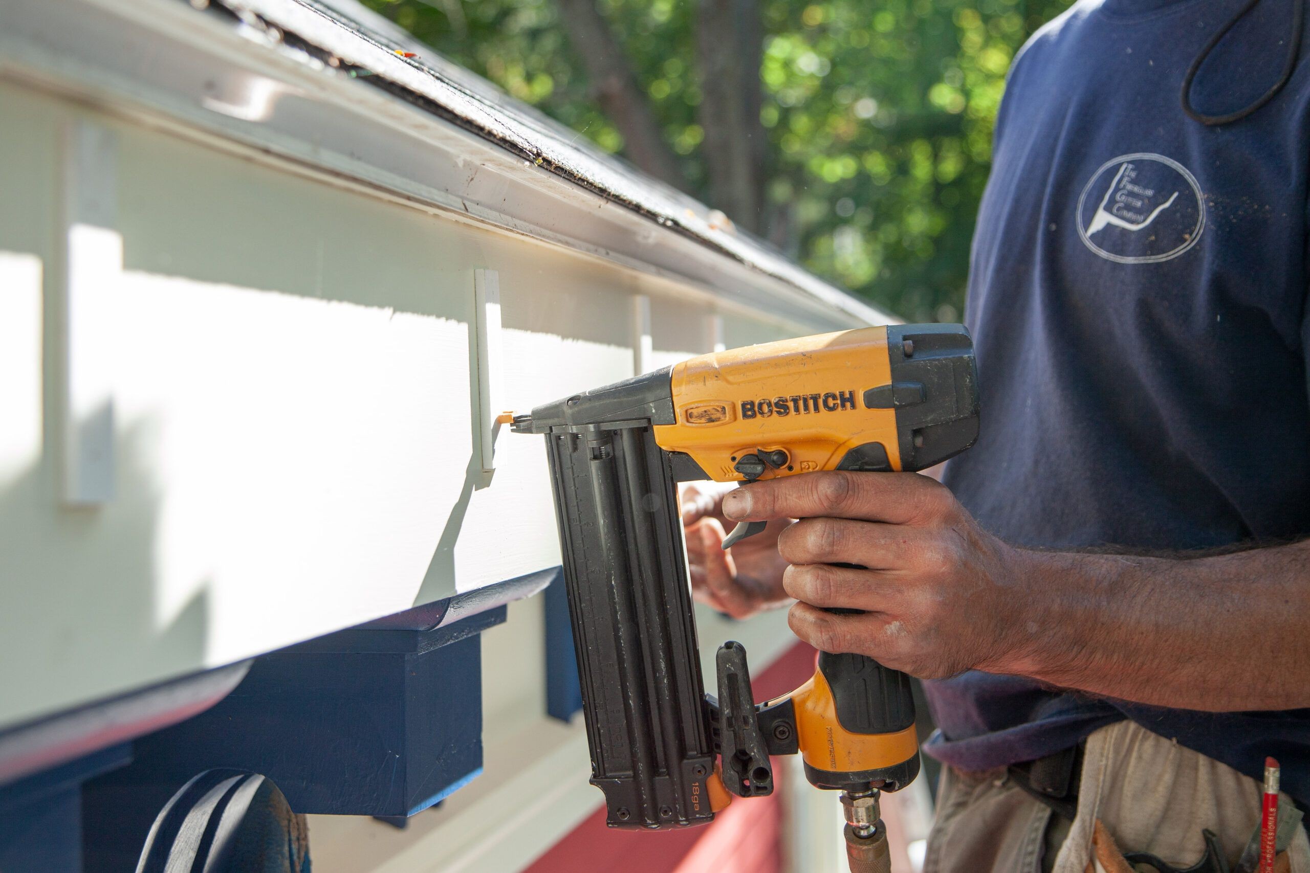 Installing a gutter bracket to the fascia board, showing the process of securing the bracket with screws