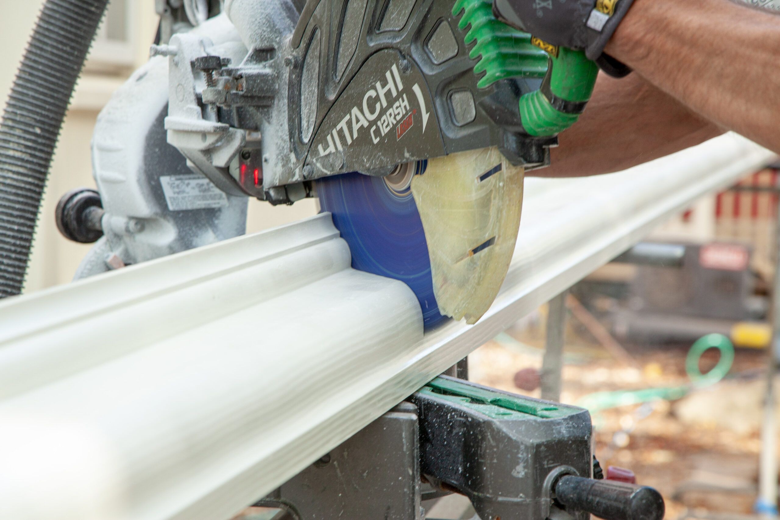 Cutting a gutter section to length using a power miter saw, showcasing the precision needed for a proper fit