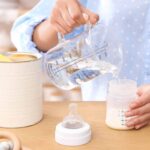 A mother preparing baby formula in a bottle.